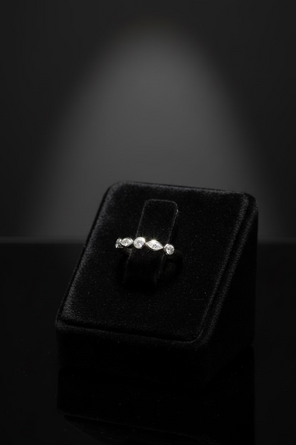 A delicate silver band ring featuring a row of marquise-cut and round-cut clear stones, photographed on a clean white background.