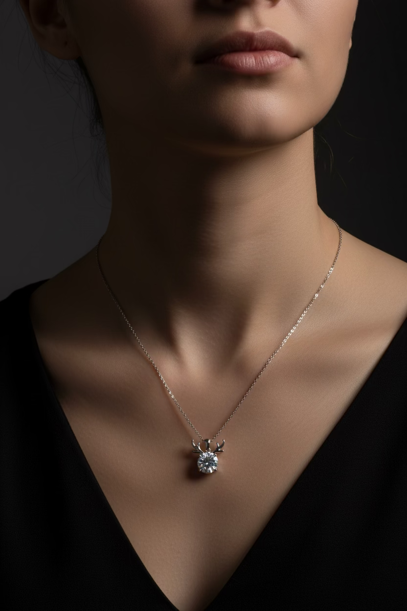 A delicate silver chain necklace featuring a small silver reindeer head pendant with a clear faceted gemstone, displayed on a clean white background.