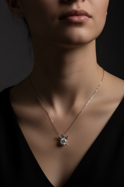 A delicate silver chain necklace featuring a small silver reindeer head pendant with a clear faceted gemstone, displayed on a clean white background.