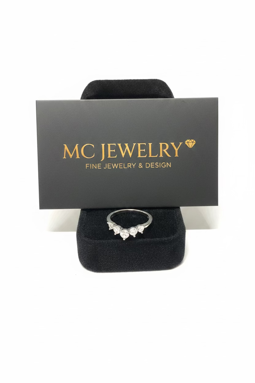 A silver ring with a small clear gemstone cluster, displayed on a black velvet ring box in front of a gray card printed with the brand name 'MC JEWELRY'.