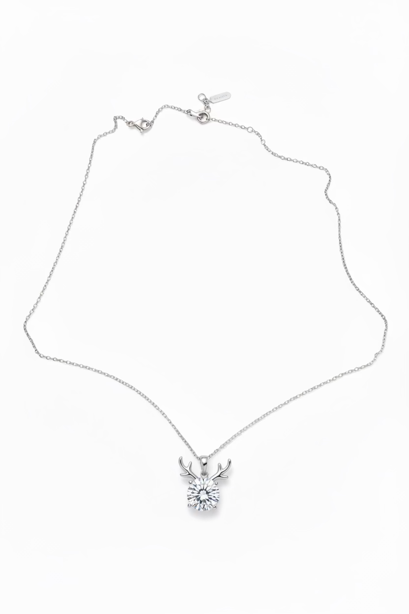 A silver-toned chain necklace with a small deer head pendant, laid out 