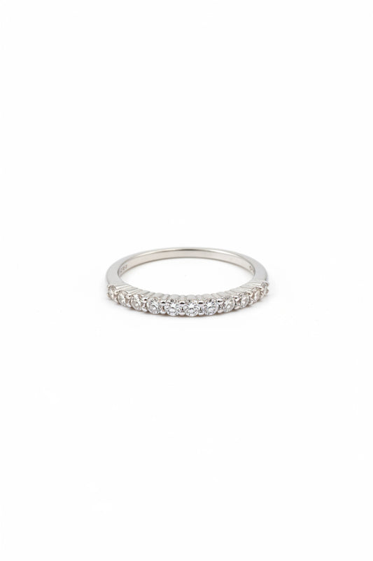A silver-toned ring with a row of small clear stones, shown resting on a person's fingers.