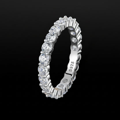 A silver eternity ring featuring round brilliant-cut diamonds set in a continuous band, shown on a solid black background. The inner band is engraved with 'S925' indicating sterling silver.