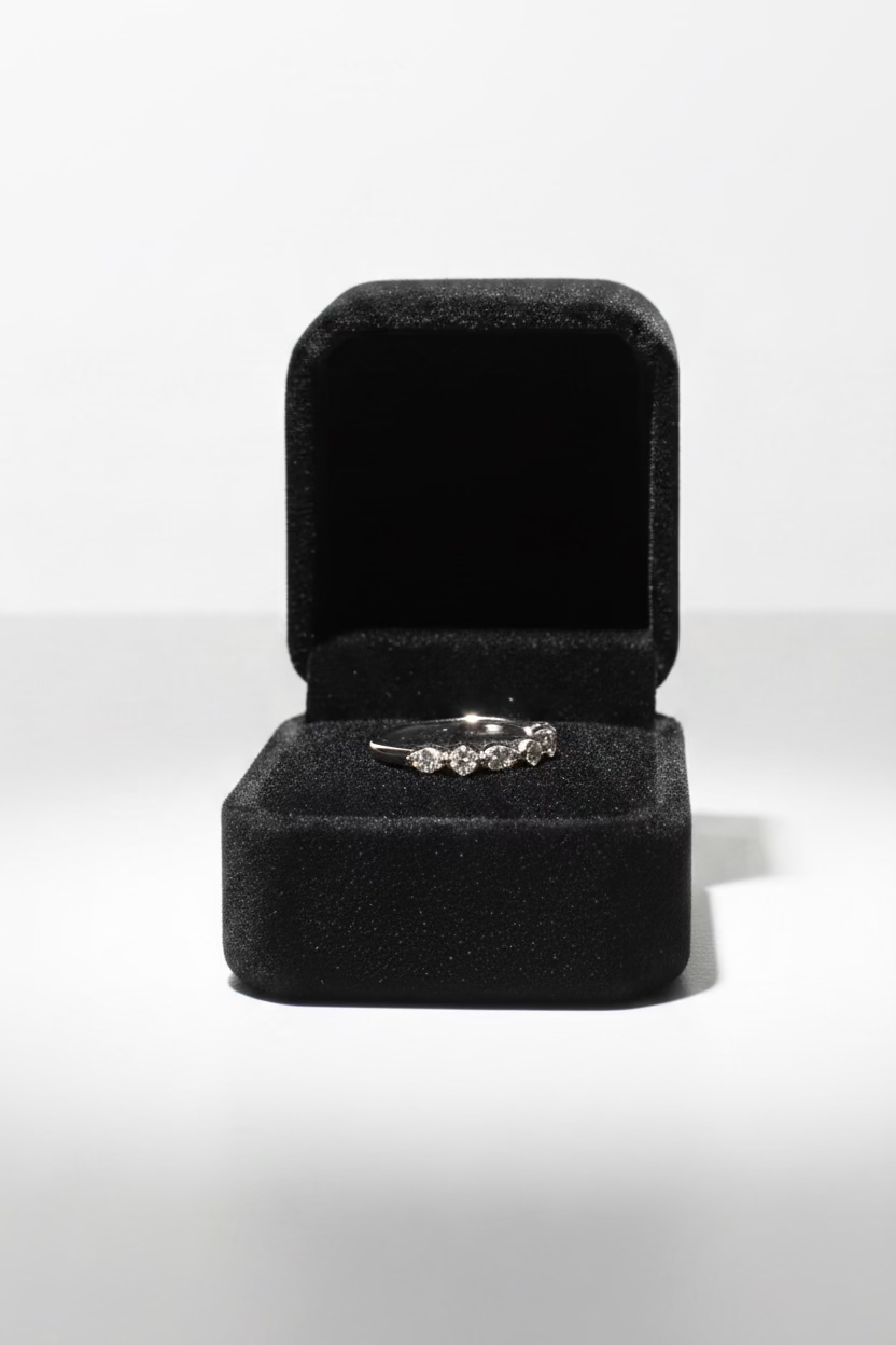 A silver ring displayed inside an open dark room gray velvet ring box on 