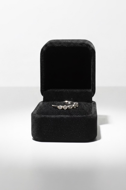 A silver ring displayed inside an open dark room gray velvet ring box on 
