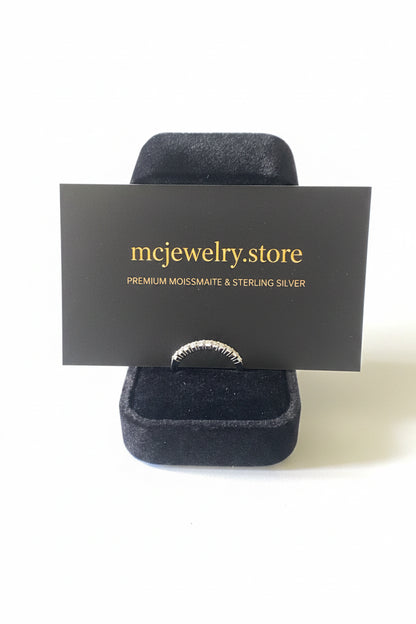 A silver ring displayed on a black velvet jewelry stand with a branded black card reading 'mcjewelry.store' in gold text, photographed against a white background.