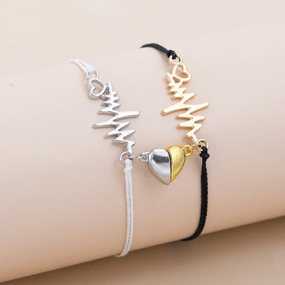 Two bracelets, one silver and one gold, on a beige surface.