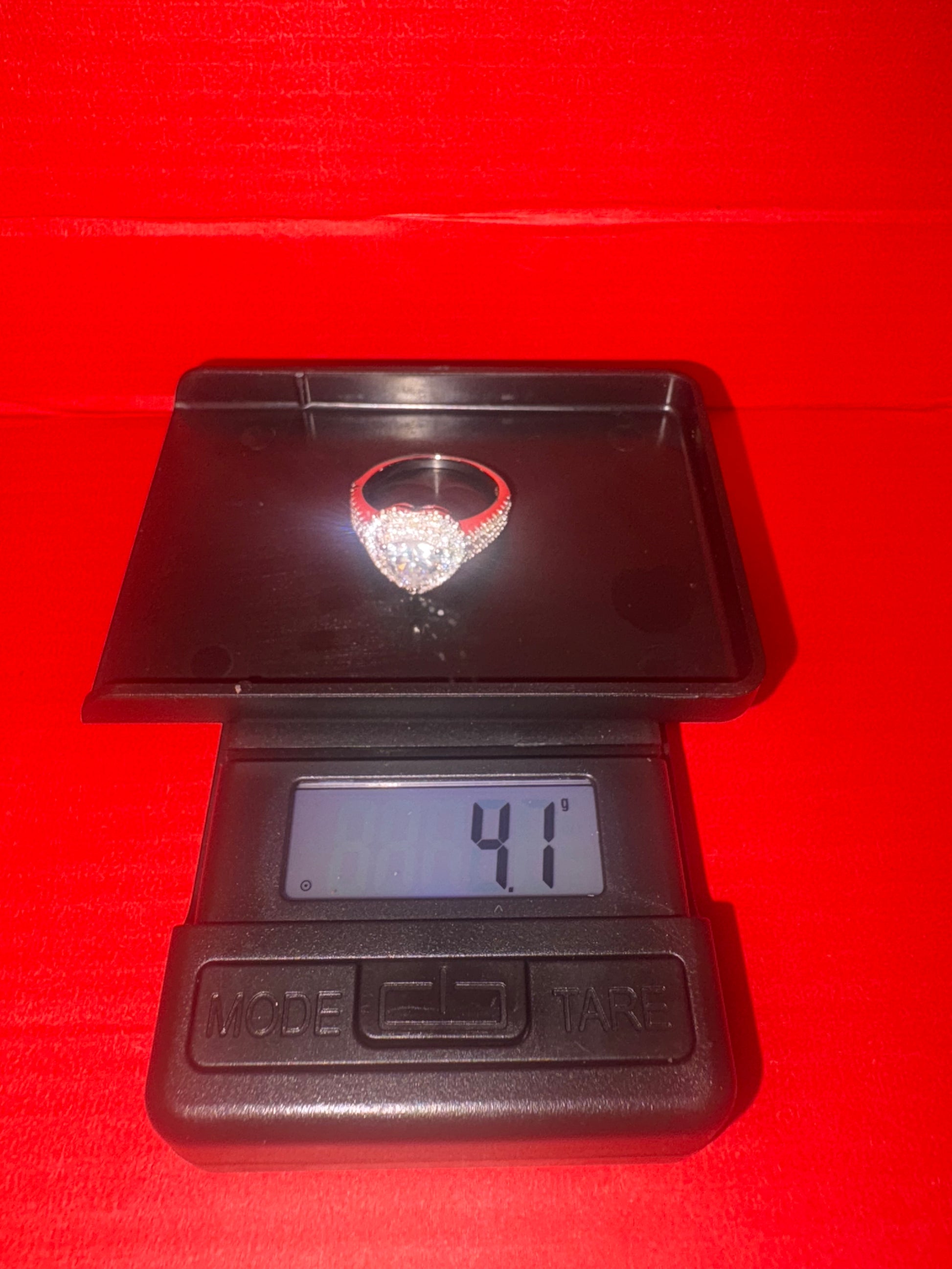 Diamond ring on a digital scale with a red background