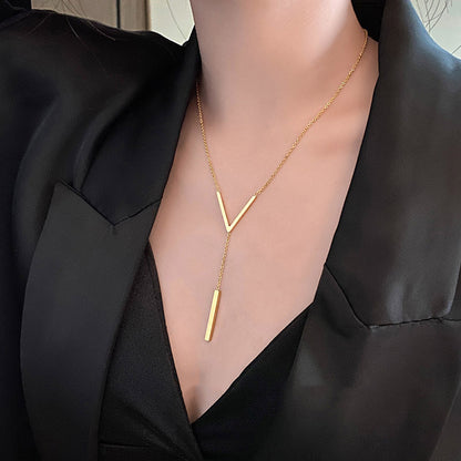 Gold necklace with a unique design worn by a person in a black outfit.