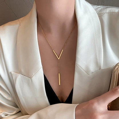 Gold necklace worn by a person of in a white outfit