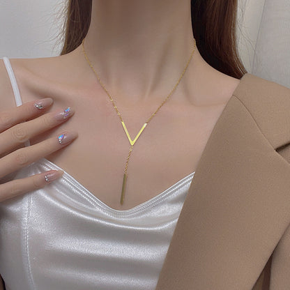 Gold necklace worn by a person with a neutral background
