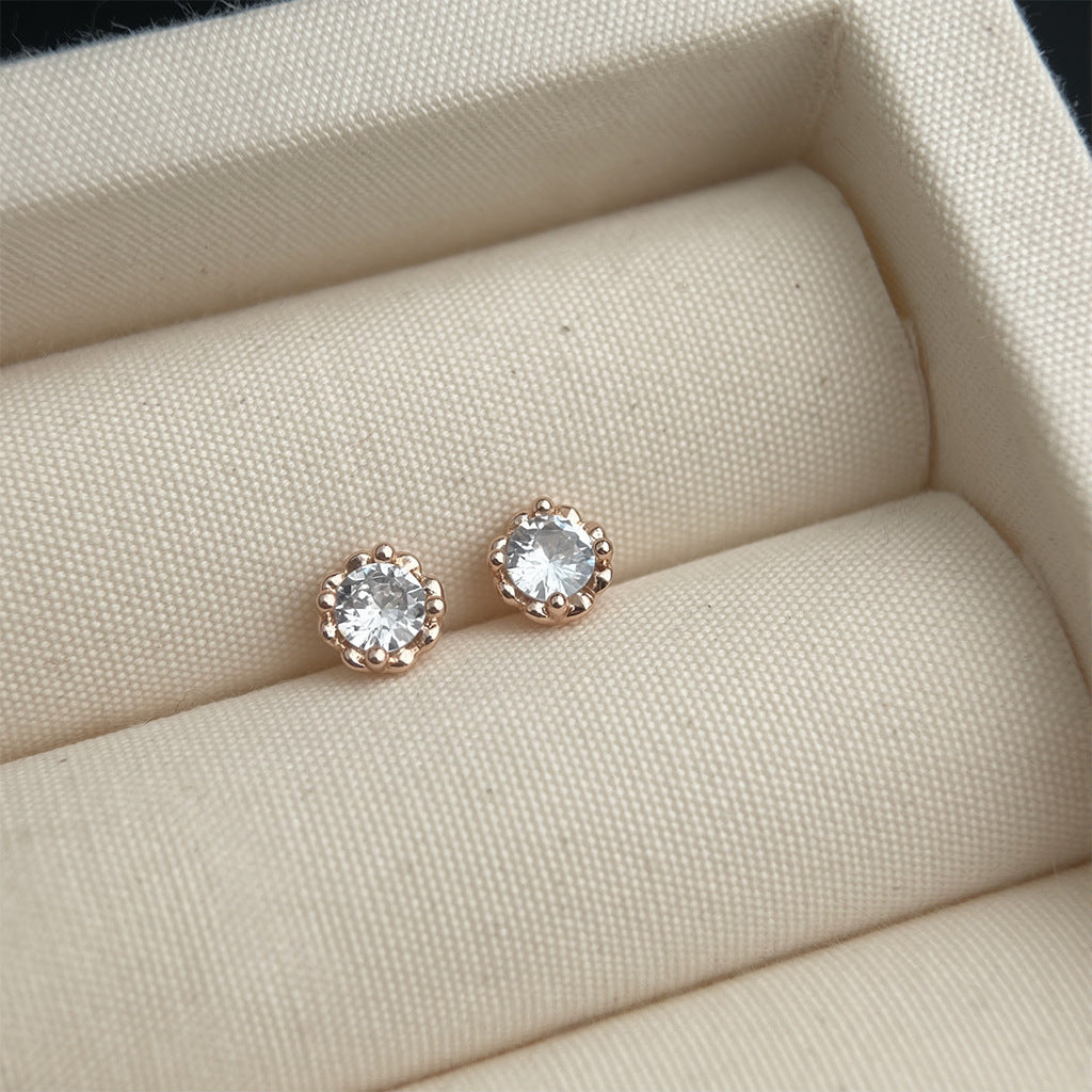 Pair of diamond stud earrings on a beige cushion in a jewelry box