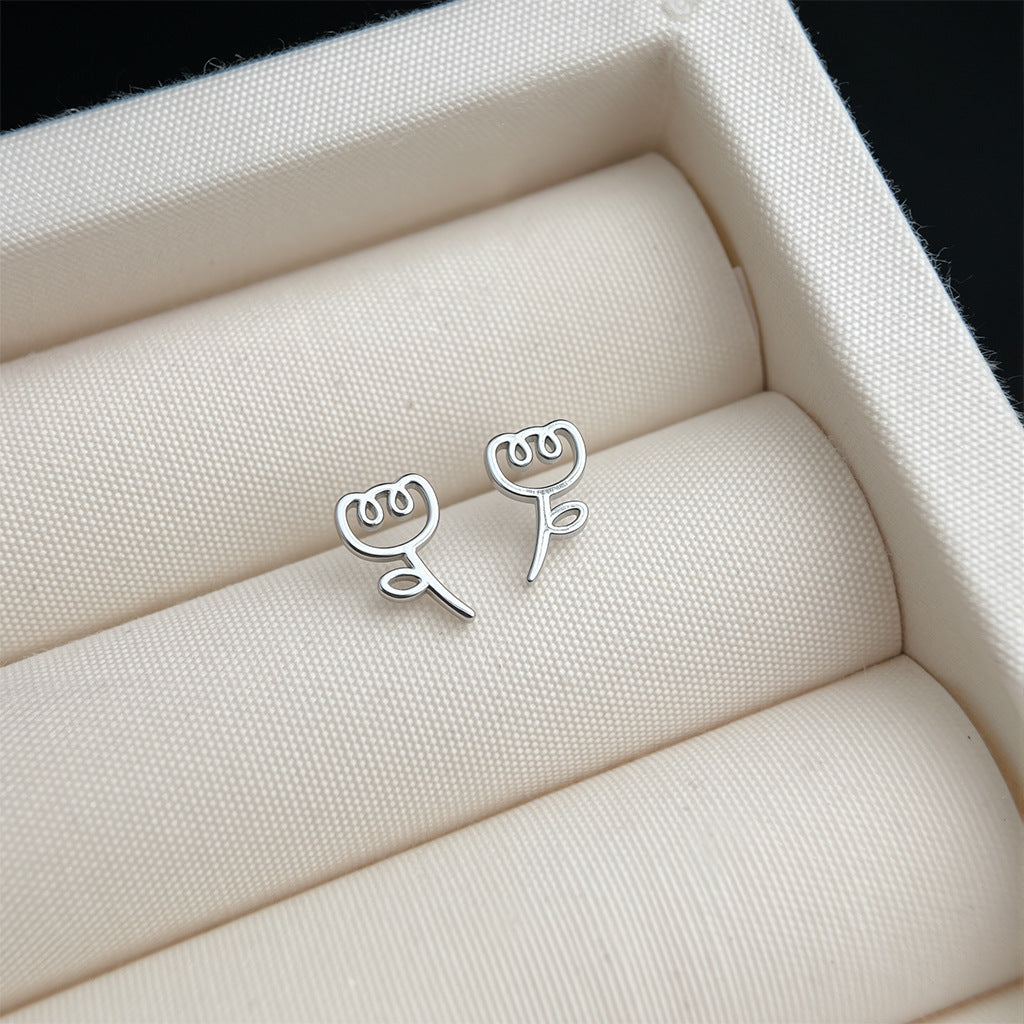 Silver flower-shaped earrings on a textured beige surface