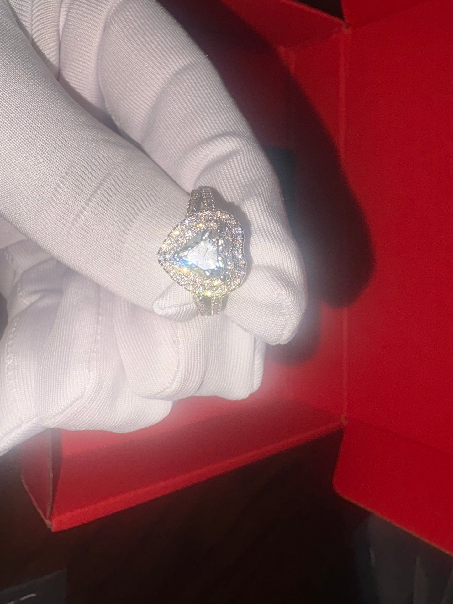 Silver ring with a large gemstone on a white cloth inside a red box.