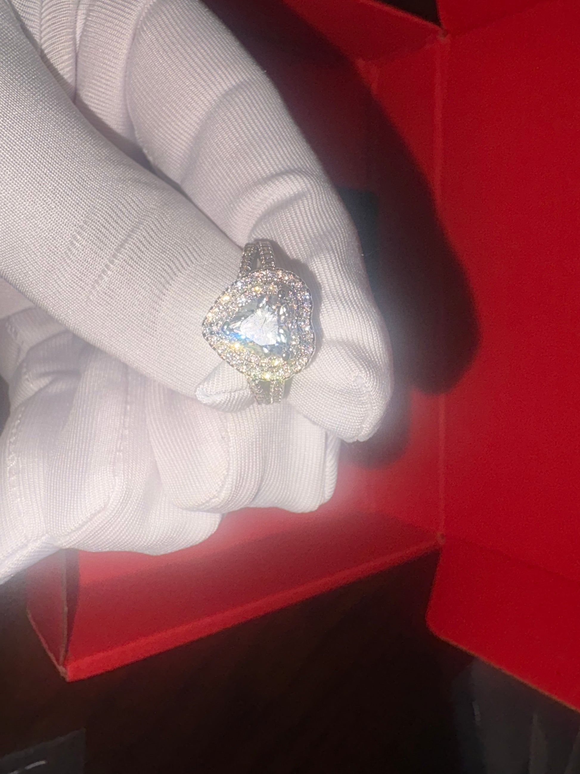 Silver ring with a large gemstone on a white cloth inside a red box.