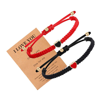 Two braided bracelets, one red and one black, with heart-shaped charms on a 'I LOVE YOU' card.