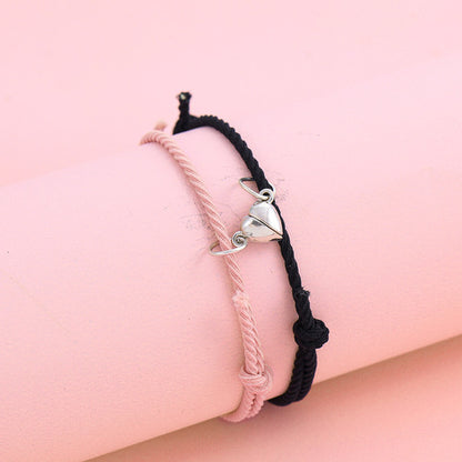 Two braided bracelets with heart charms on a pink background