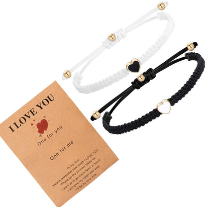 Two macrame bracelets, one white and one black, with heart-shaped beads on a 'I LOVE YOU' card.